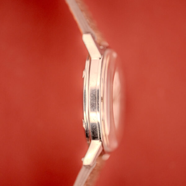 An Omega Seamaster Automatic "Red Crosshair" Ref. 165.002 Cal. 552 wristwatch, shown from the side against a solid red background.