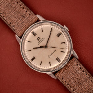 An Omega Seamaster Automatic "Red Crosshair" Ref. 165.002 Cal. 552 with a red crosshair dial and tan textured strap, displayed on reddish-brown leather.