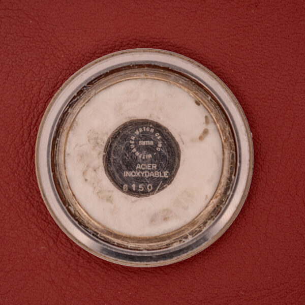 The Wittnauer Electro-Chron "Lightning Bolt" Tropic Dial Ref. 6150 features a round metal case back with engraved text, shown here on a red textured surface.