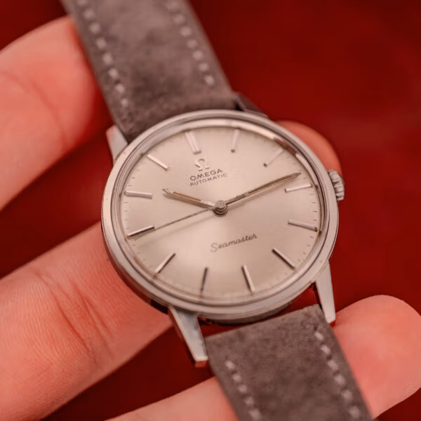 Macro hand-held shot of Omega Seamaster 165.002 silver sunburst dial highlighting applied markers and aged tritium hands