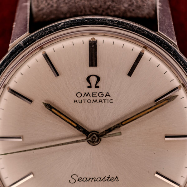 Close-up of an Omega Seamaster Automatic Ref. 165.002 watch face with black hour markers, silver hands, and powered by the renowned Cal. 552 movement.