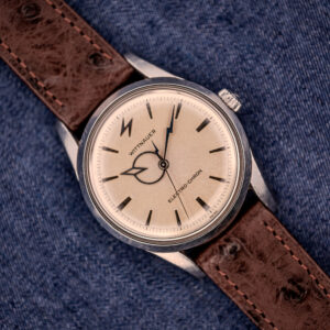 A Wittnauer Electro-Chron "Lightning Bolt" Ref. 6150/2 Cal. 11EW c.1962 with a brown leather strap, shown on blue fabric, highlights the timeless appeal of this iconic vintage wristwatch design.