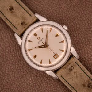 The Omega Transitional Calendar Bumper Automatic Ref. 2438-2 Cal. 353 (c.1951) features a cream dial with date at 3 o’clock, Cal. 353 automatic movement, and a tan leather strap.