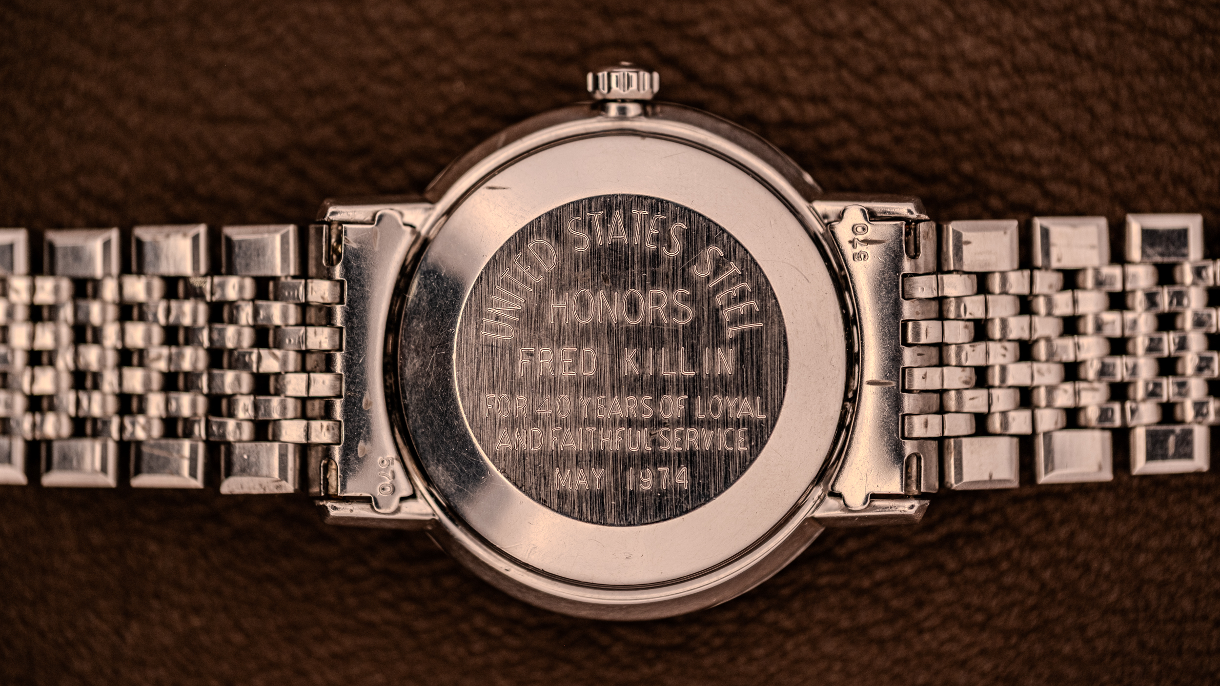 Close-up of a vintage Omega Seamaster DeVille silver wristwatch back, engraved with an inscription honoring Fred Killin for loyal service.