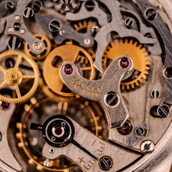 Close-up of intricate gears and mechanisms on the Jaeger Tri-Compax Chronograph Ref. 22522 Stainless Steel Cal. UG 285, showcasing engraved details—a testament to the precision craftsmanship behind each chronograph masterpiece.
