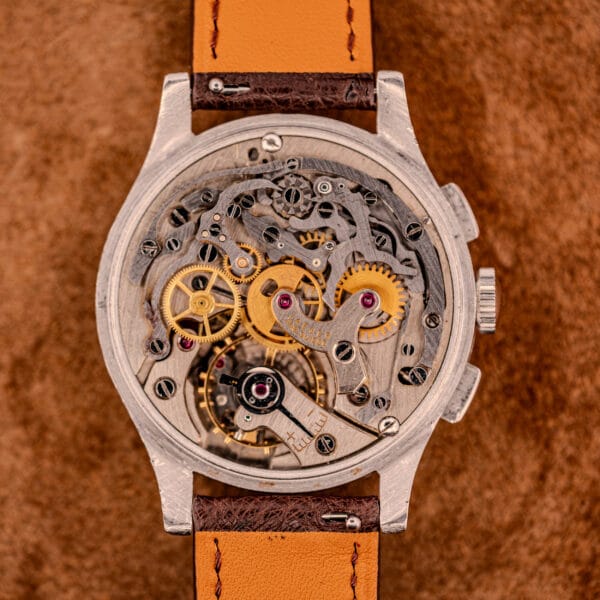 Close-up of the Jaeger Tri-Compax Chronograph Ref. 22522 in stainless steel, showcasing its exposed gears and intricate Cal. UG 285 movement, complemented by a brown leather strap.