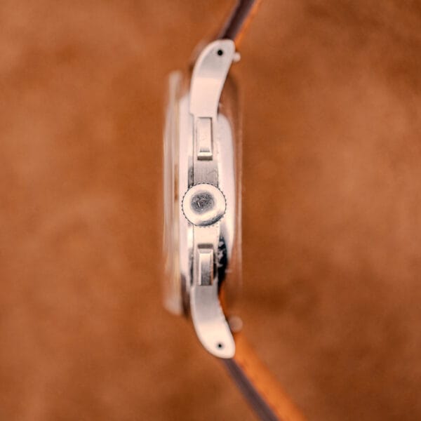 Side view of a Jaeger Tri-Compax Chronograph Ref. 22522 in stainless steel with Cal. UG 285, shown with a brown leather strap on a brown textured background.