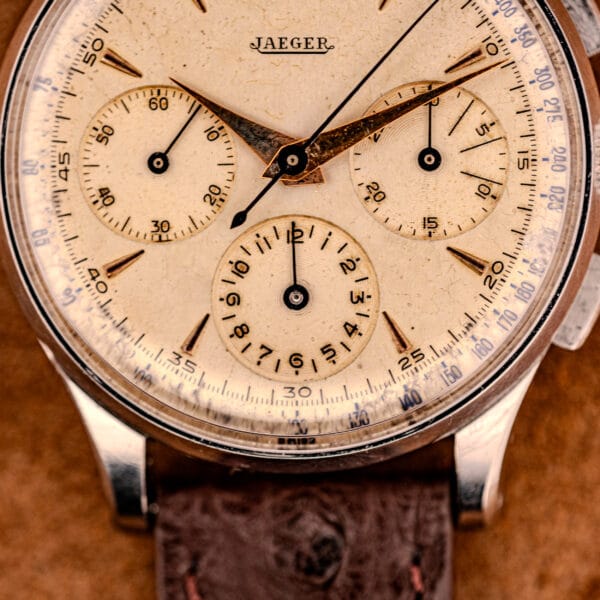 Close-up of a vintage Jaeger Tri-Compax Chronograph Ref. 22522 in stainless steel with Cal. UG 285, featuring a beige dial and brown leather strap.