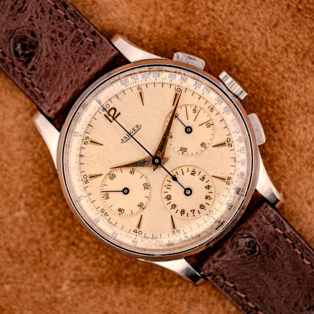 The Jaeger Tri-Compax Chronograph Ref. 22522, featuring a tan dial and brown leather strap, is showcased on suede to emphasize its classic stainless steel case and Cal. UG 285 movement.