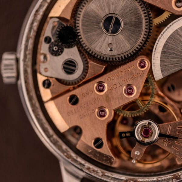 Close-up of the Hamilton Automatic Silver Sunburst Micro-Rotor Cal. 666 watch movement, highlighting its intricate gears, screws, and engraved components beneath the refined Silver Sunburst finish.