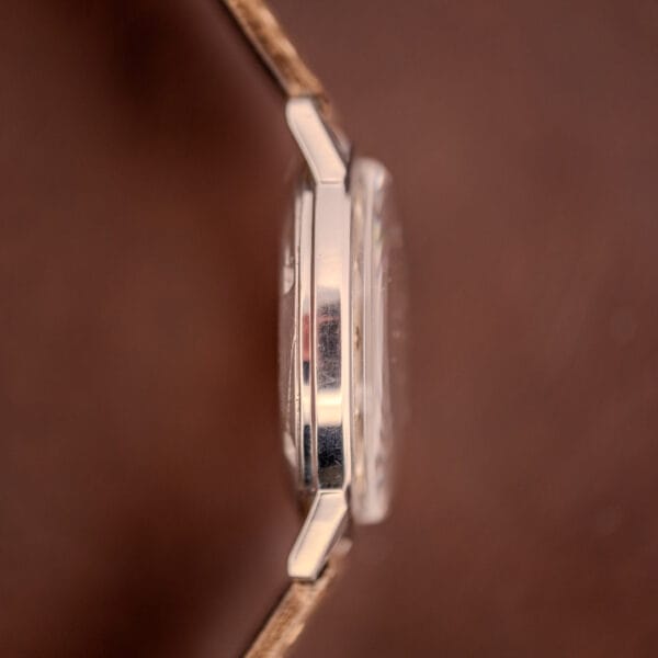 Side view of the Hamilton Automatic Silver Sunburst Micro-Rotor Cal. 666 with a brown leather strap, shown against a blurred brown background.