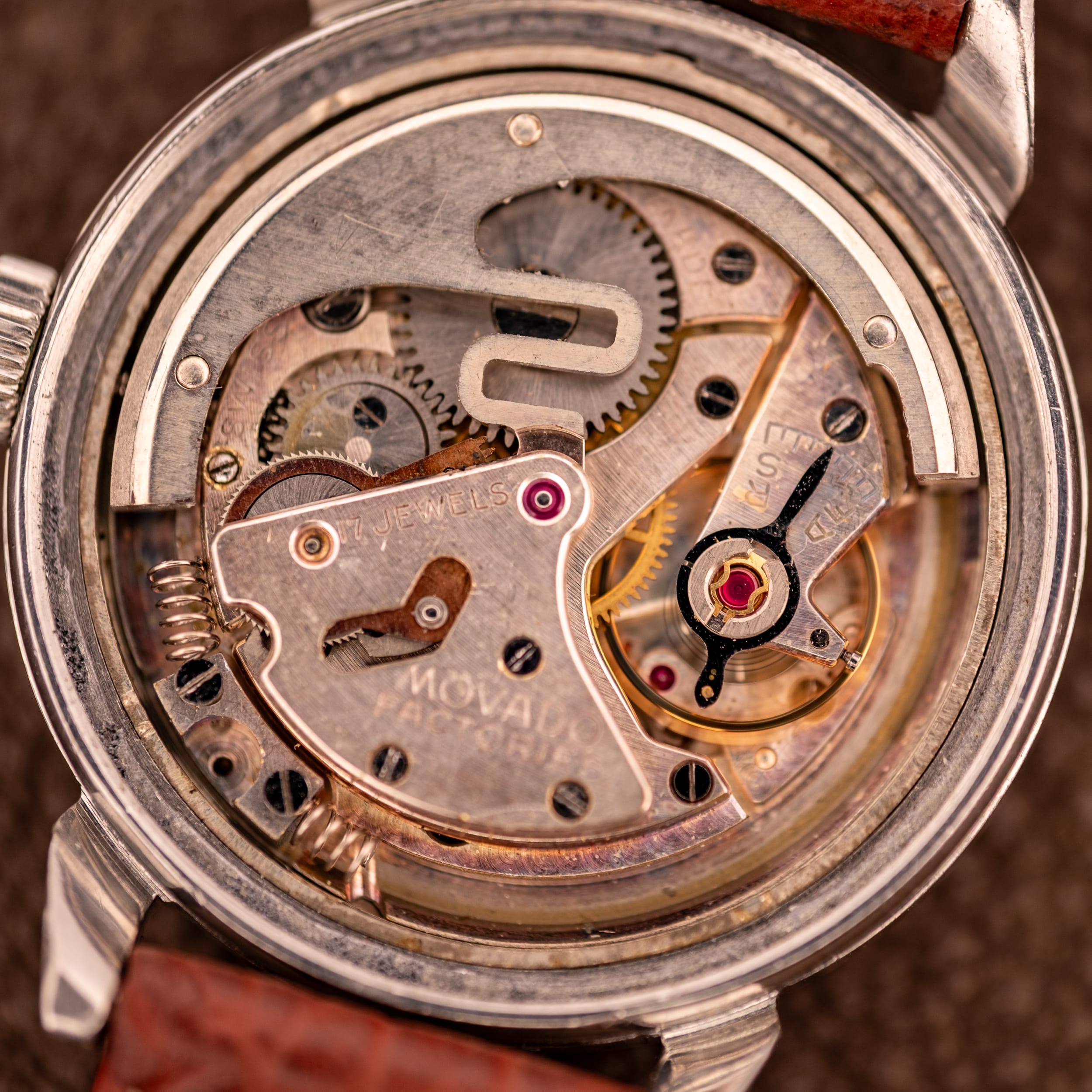 Close-up view of a vintage movado 115 mechanical watch movement, featuring visible gears, jewels, metal components, and the distinctive bumper movement mechanism.