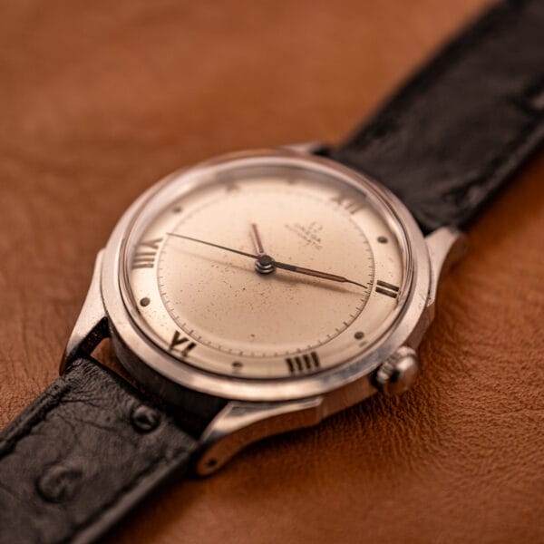 Omega Automatic Bumper 2584-1 angled top-down on tan leather, cream dial and downturned faceted lugs visible