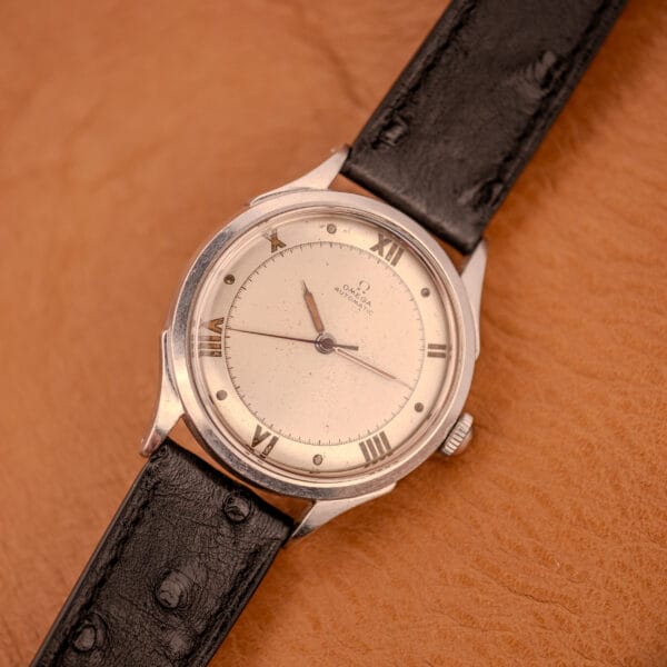 Omega Automatic Bumper 2584-1 angled top-down on terracotta backdrop, complete watch with black ostrich strap