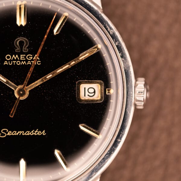 Omega Seamaster 166.002 dial macro with Omega-signed crown and white-on-black gilt-framed date window