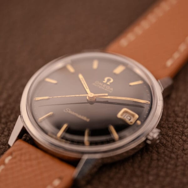 Omega Seamaster 166.002 black gilt dial at an angle showing depth of the gloss black field and gold-tone dauphine hands