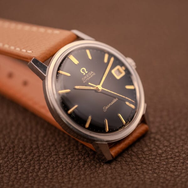 Omega Seamaster 166.002 three-quarter view on tan grained leather strap with gold-tone hour markers and date at three