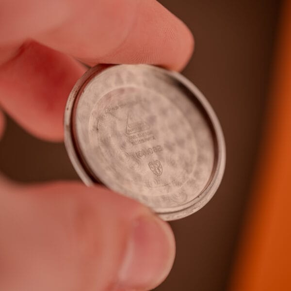 Omega Seamaster 166.002 inner caseback held in fingers showing reference 166.002 and Omega Watch Co. stampings
