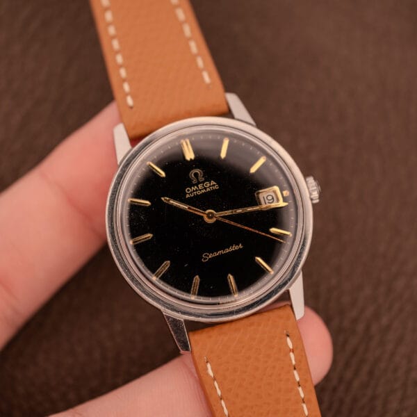 Omega Seamaster 166.002 held in hand showing factory black gilt dial and steel Seamaster case