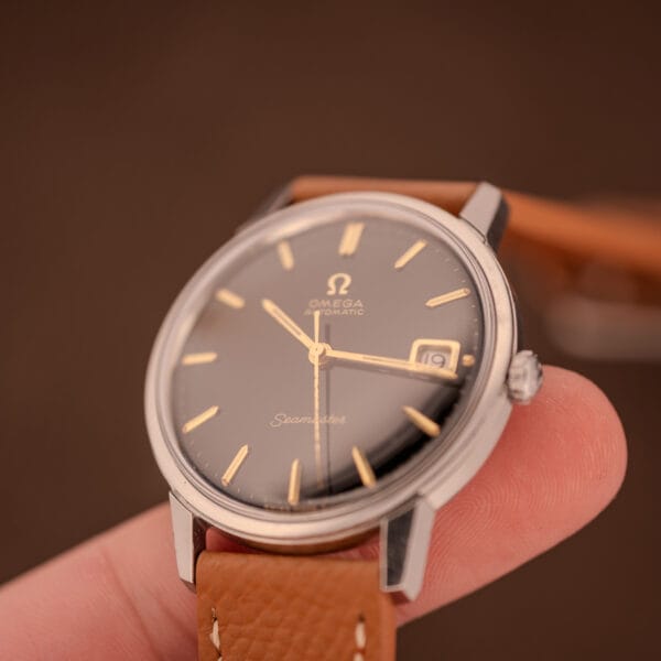 Omega Seamaster 166.002 between fingers, angled three-quarter view of dial, crown and lugs
