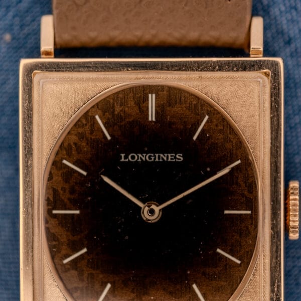 Longines Tank 3217-428 dial close-up showing the printed LONGINES wordmark over a chocolate Leopard-patina field with applied gold stick markers