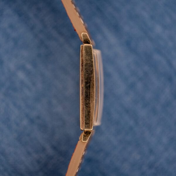 Macro of the left case side of the Longines Tank ref 3217-428 in 10k gold filled, honest wear visible across the polished surface