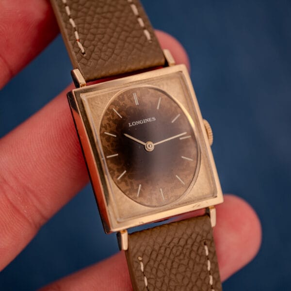 In-hand wrist-context shot of the vintage Longines Tank watch ref 3217-428 with Leopard dial visible under raking light