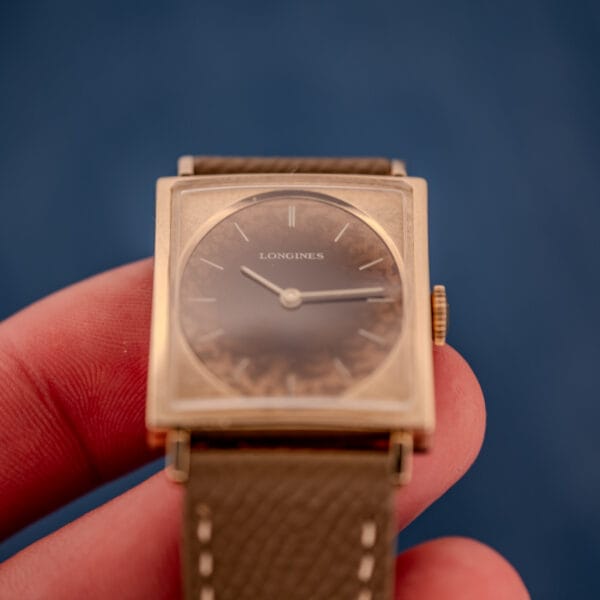 Front-on in-hand view of the Longines Tank 3217-428 showing the dial gradient and the florentine 10k gold filled case frame