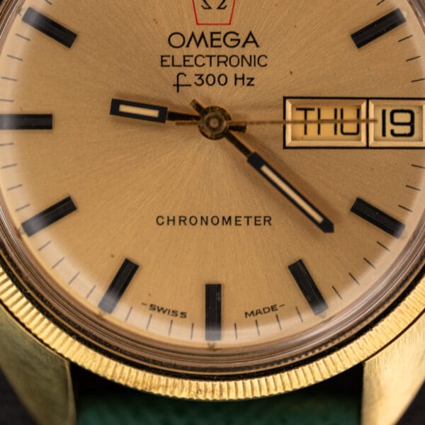 Macro of the Omega F-300 Hz dial lower half with printed CHRONOMETER wordmark, SWISS MADE under six, and the period-correct gold sweep seconds hand