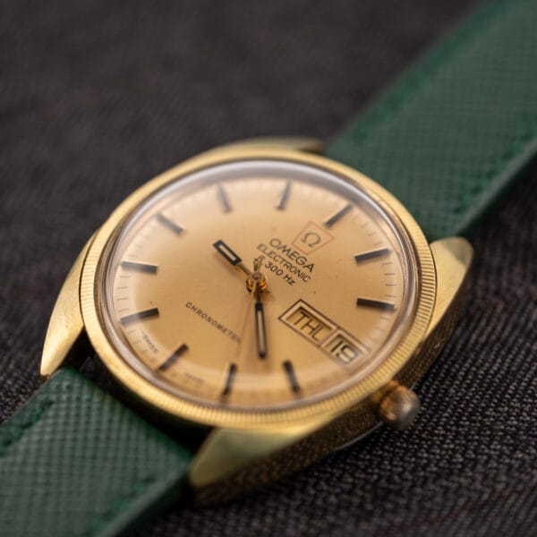 Top-down view of the Omega Electronic F-300 Hz ref. 1980045 in a 35.2mm fluted gold-plated case on a green saffiano strap