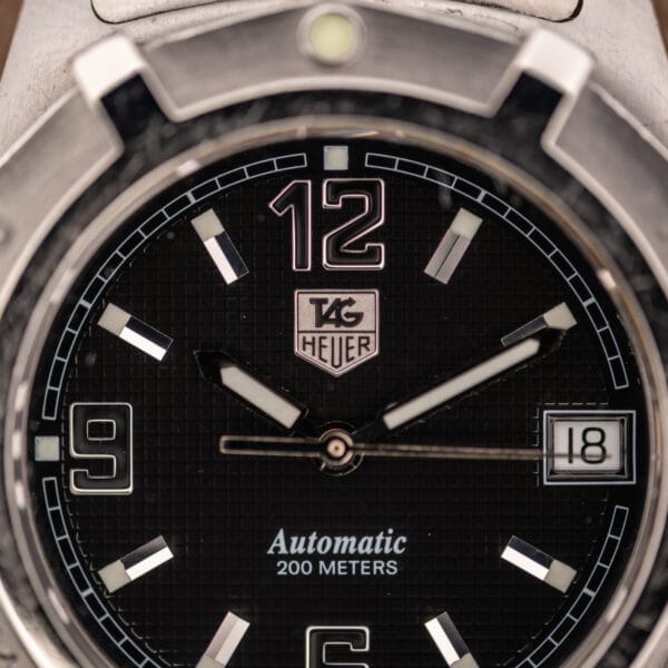 TAG Heuer WN2111 waffle dial close-up showing applied steel 12, 6, 9 numerals and SuperLuminova-filled stick markers