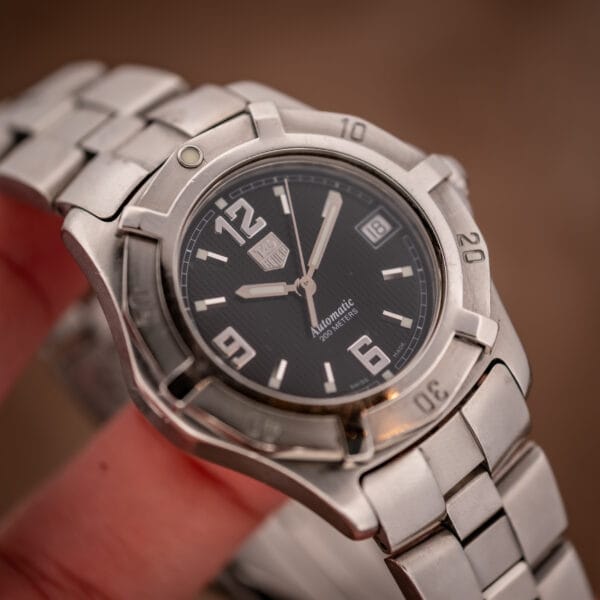 TAG Heuer 2000 Series WN2111 case and bracelet held in hand with crown and bezel detail