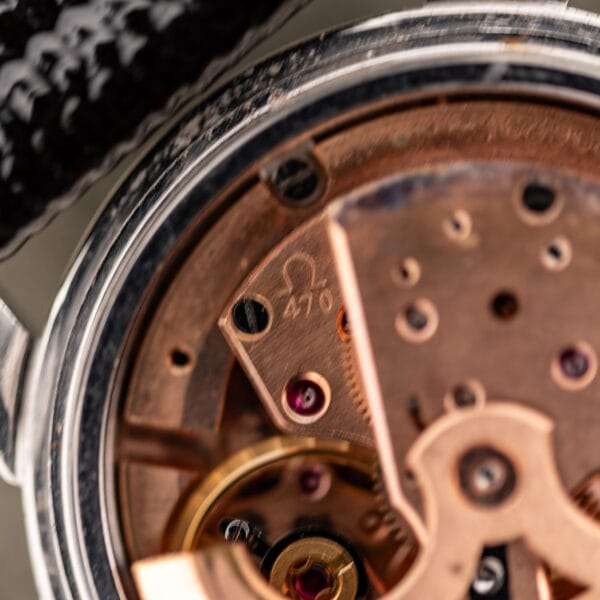 Omega caliber 470 movement closeup with Omega symbol and caliber stamping on copper bridge