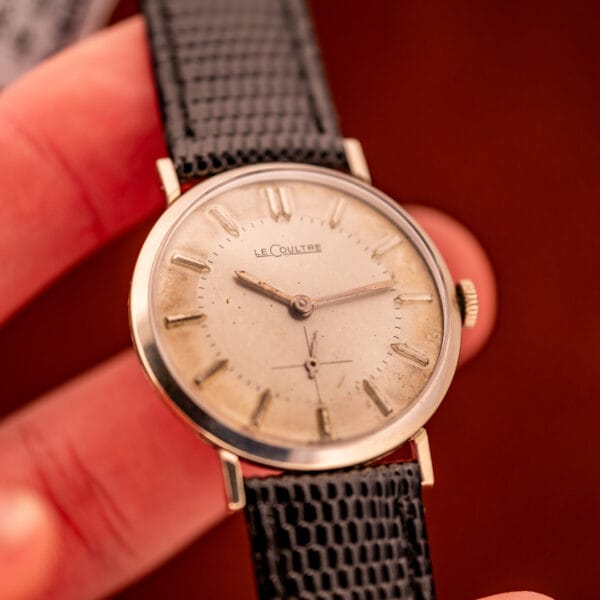 Vintage LeCoultre 3022 held in hand, angled dial view showing honey patina and signed LeCoultre wordmark