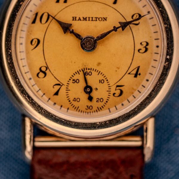 1936 Hamilton Randolph dial and crown close-up against denim with honey-aged cream Art Deco surface