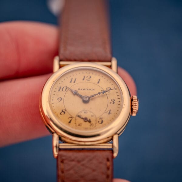 1936 Hamilton Randolph held in hand showing honey-patinated cream dial, cathedral hands, and rose-toned signed crown