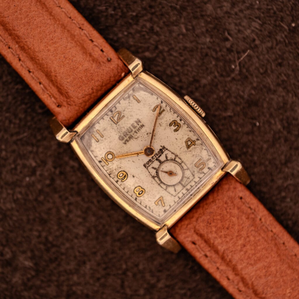 Vintage Gruen Precision Ref. 430-457 watch top-down with tan leather strap on dark suede