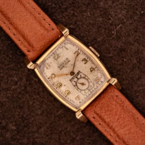 Vintage Gruen Precision Ref. 430-457 watch top-down with tan leather strap on dark suede