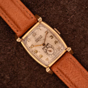 Vintage Gruen Precision Ref. 430-457 watch top-down with tan leather strap on dark suede