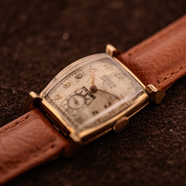 Vintage Gruen Precision tank watch three-quarter angle, factory spotted-silver dial and tan leather strap
