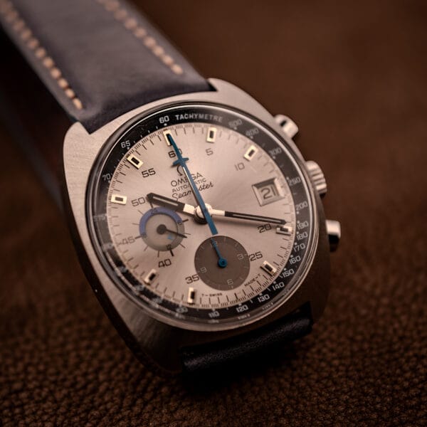 Omega 176.007 Blue Jedi wider angled shot showing tachymetre flange and silver sunburst dial against a soft background
