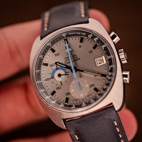 Omega Seamaster 176.007 Blue Jedi held in hand at wear-style angle on navy grained leather strap with signed buckle