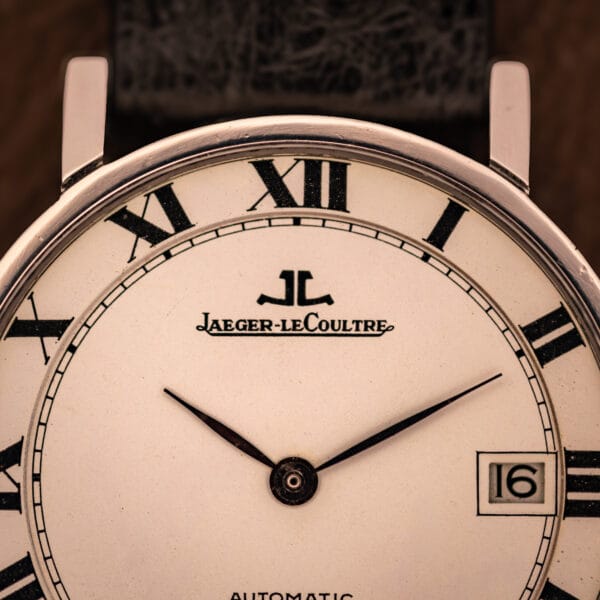 Jaeger LeCoultre Ultra Thin upper-dial macro showing applied JL monogram, cursive Jaeger-leCoultre signature, and inner railroad minute track.