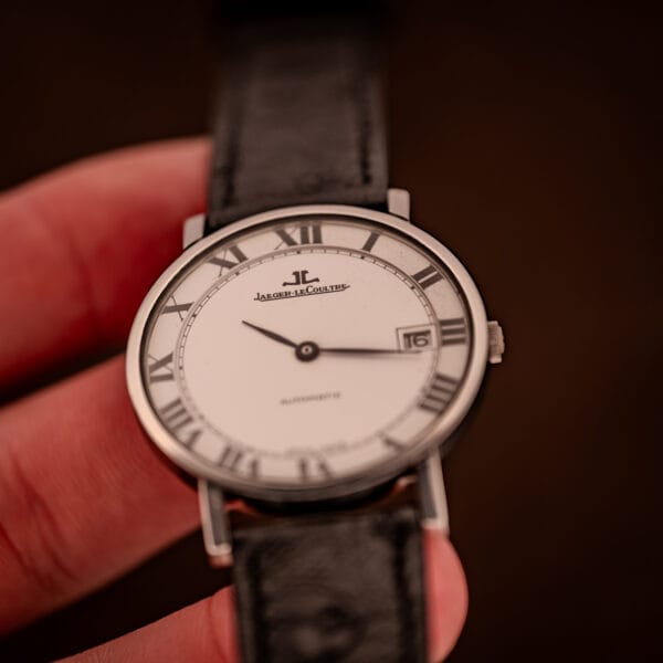 Jaeger LeCoultre Ultra Thin angled in hand, factory dial with applied JL monogram and full Roman numeral chapter ring.