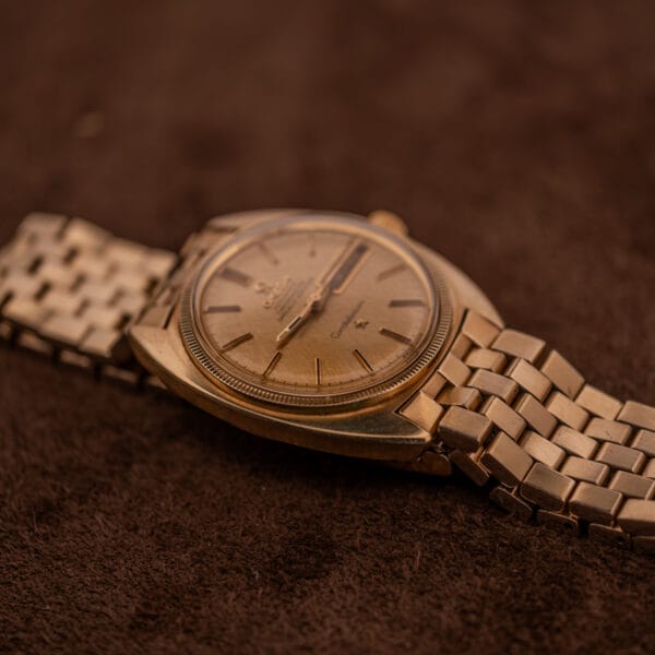 Omega Constellation 168.029 cushion case profile with fluted bezel and integrated gold bracelet on suede