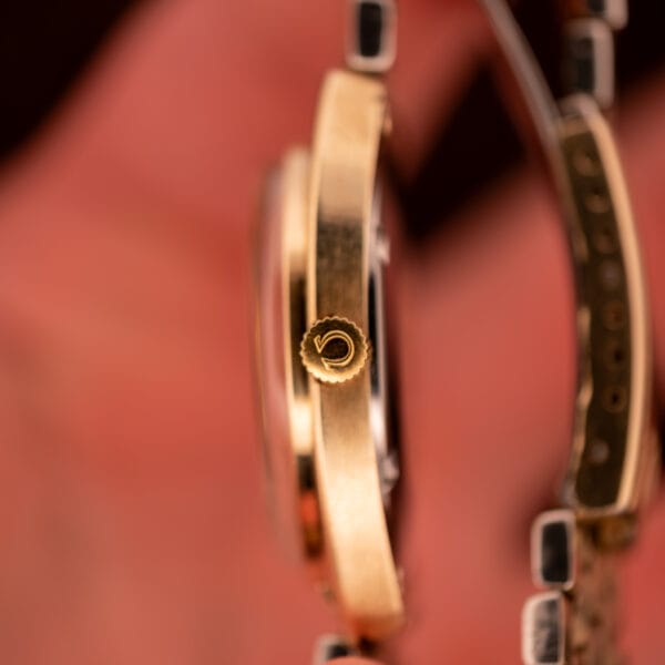 Omega Constellation 168.029 signed Omega crown macro view in 14k gold against red background