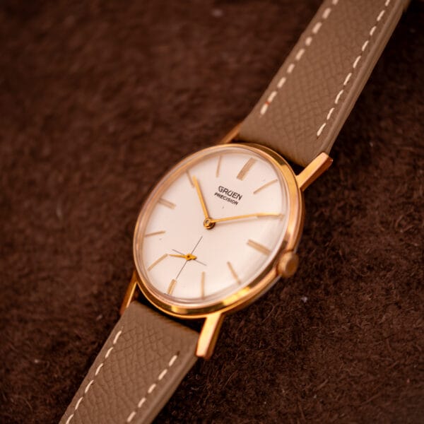 Vintage Gruen Precision 510 high angle with cream dial, gold dauphine handset, and grey saffiano leather strap