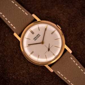 Vintage Gruen Precision 510 cream dial with gold dauphine hands and 12 3 6 9 triple-line markers on grey saffiano strap