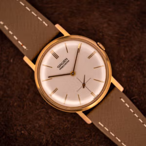 Vintage Gruen Precision 510 cream dial with gold dauphine hands and 12 3 6 9 triple-line markers on grey saffiano strap