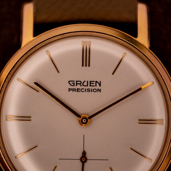 Gruen Precision 510 dial macro showing GRUEN PRECISION signature, triple-line 12 marker, and applied gold baton hour batons